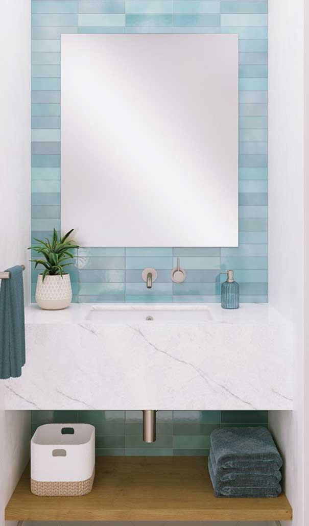 Modern bathroom vanity with white marble countertop, blue tile wall, and large mirror; plant and soap bottle on counter.